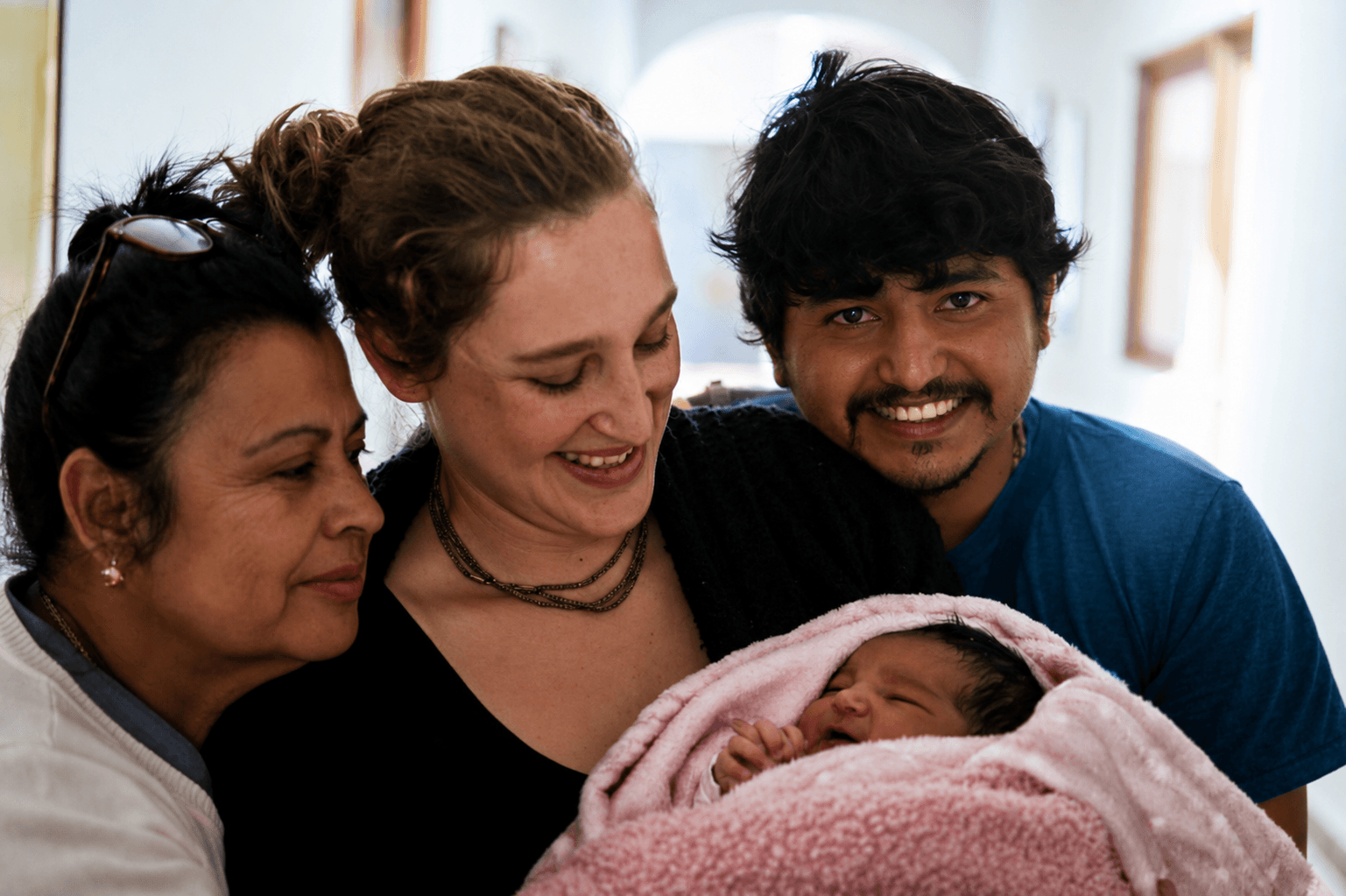 Una madre sostiene a su bebé junto a su acompañante y una integrante del equipo de atención.