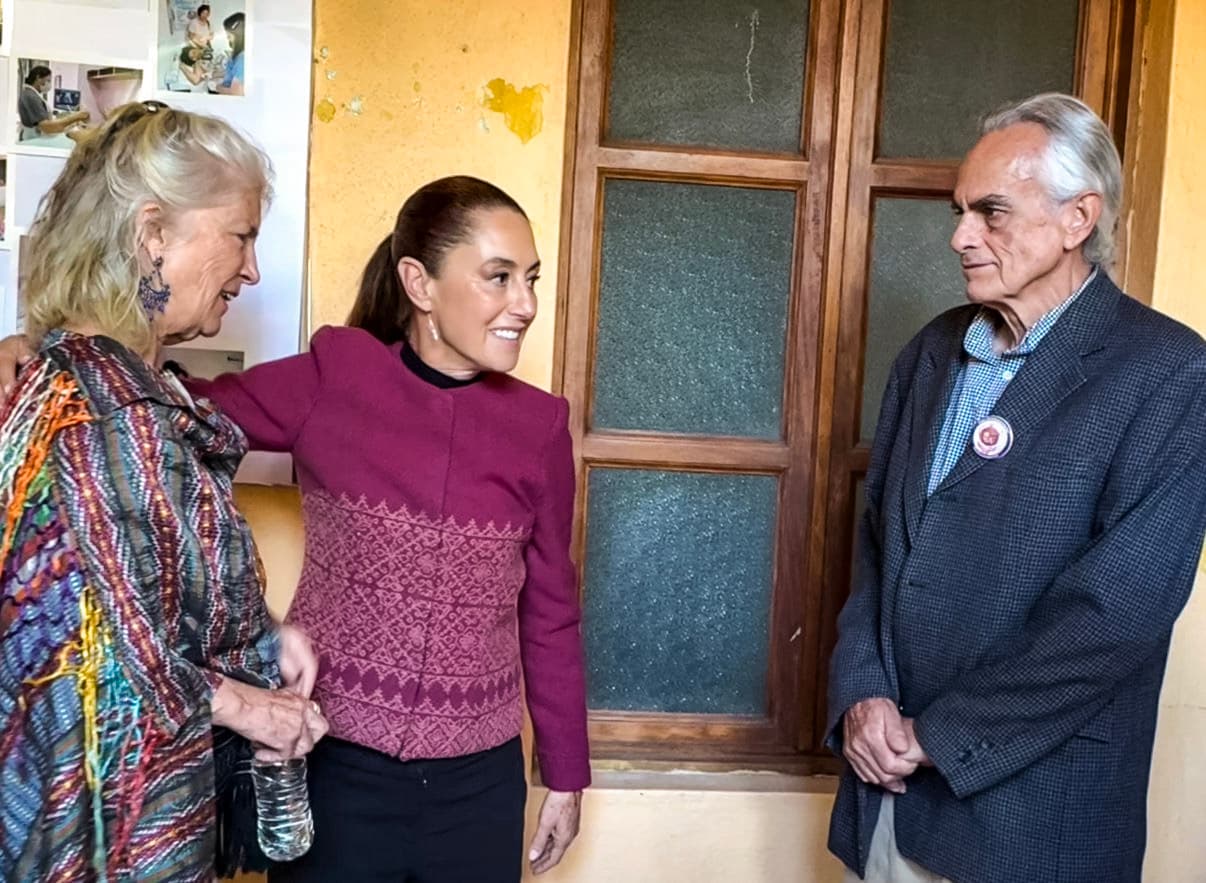 Tres personas conversan junto a una puerta de madera durante un encuentro en el Centro.